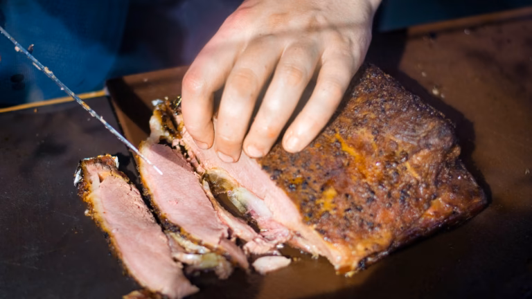 Cook slicing meat while preparing a meal for an Old Smokey Electric Smoker review.